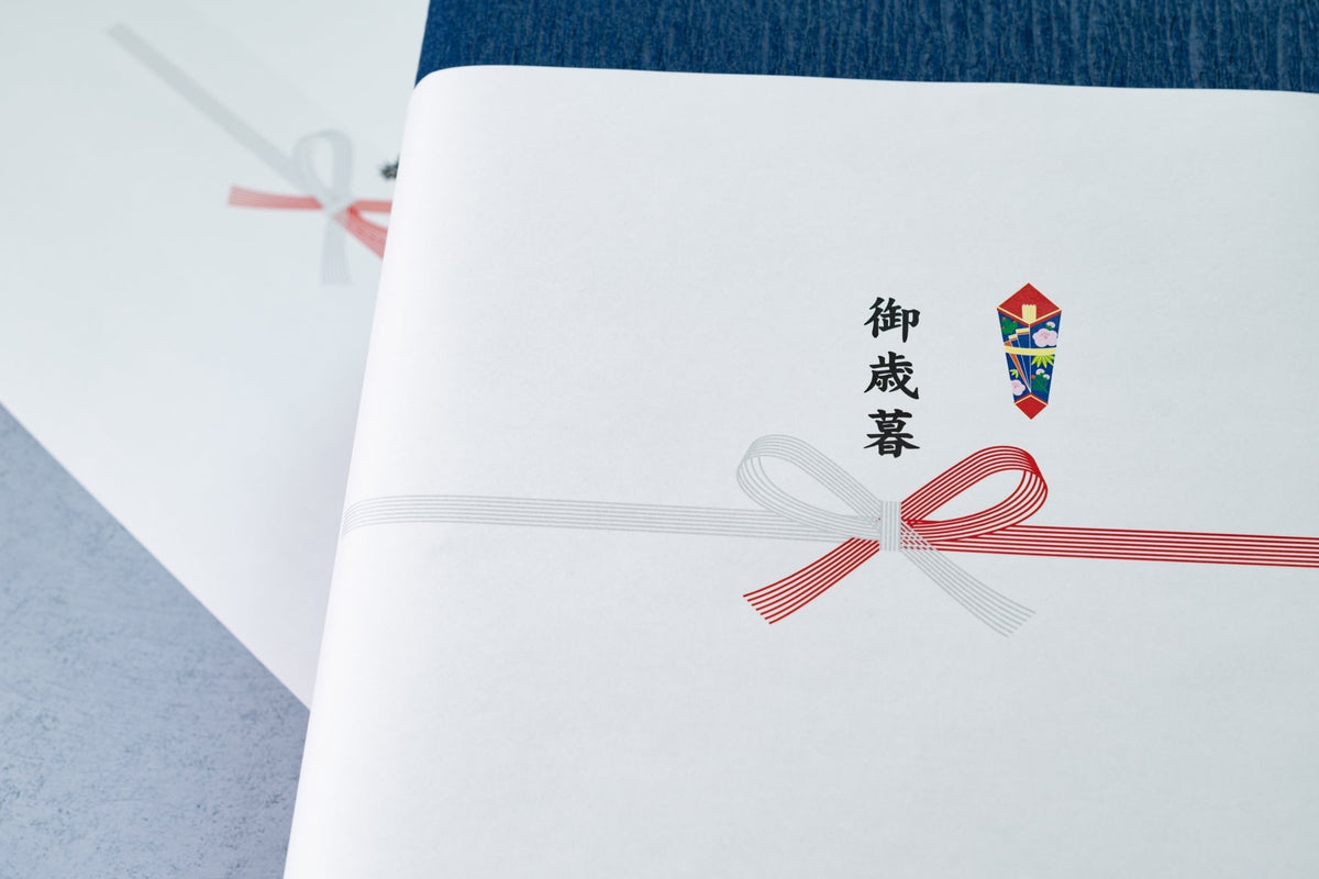 紅白の蝶結びの水引と熨斗が印刷され、「御歳暮」と書かれたのし紙を掛けた箱が、もう一つの箱と重ねて置かれている