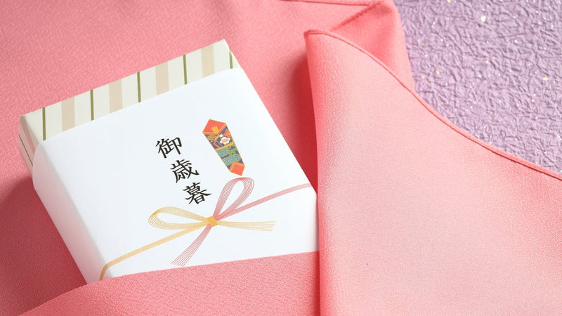 「御歳暮」と書かれたのし紙を掛けた箱を、ピンクの袱紗で包みかけているところ