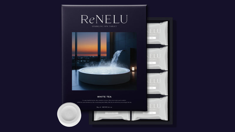 濃い紺の背景に置いた、高級入浴剤ギフトの ReNELU SPARKLING SPA TABLET の化粧箱と、白い個包装・錠剤