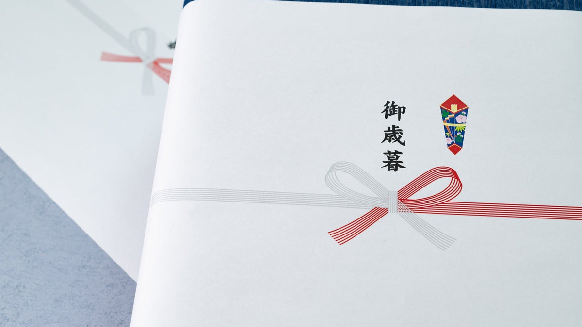 紅白の蝶結びの水引と熨斗が印刷され、「御歳暮」と書かれたのし紙を掛けた箱が、もう一つの箱と重ねて置かれている