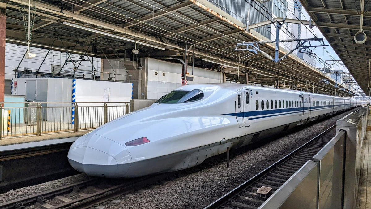 駅のホームに停まる白い車体に青い線の新幹線